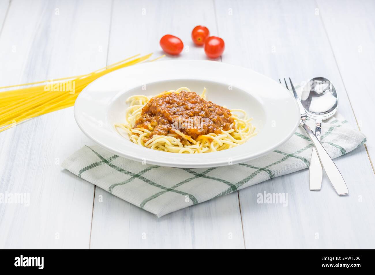 Délicieux bolognaise spaghetti avec sauce à la viande avec nappe sur table en bois blanc avec de la matière première à l'arrière-plan. Banque D'Images