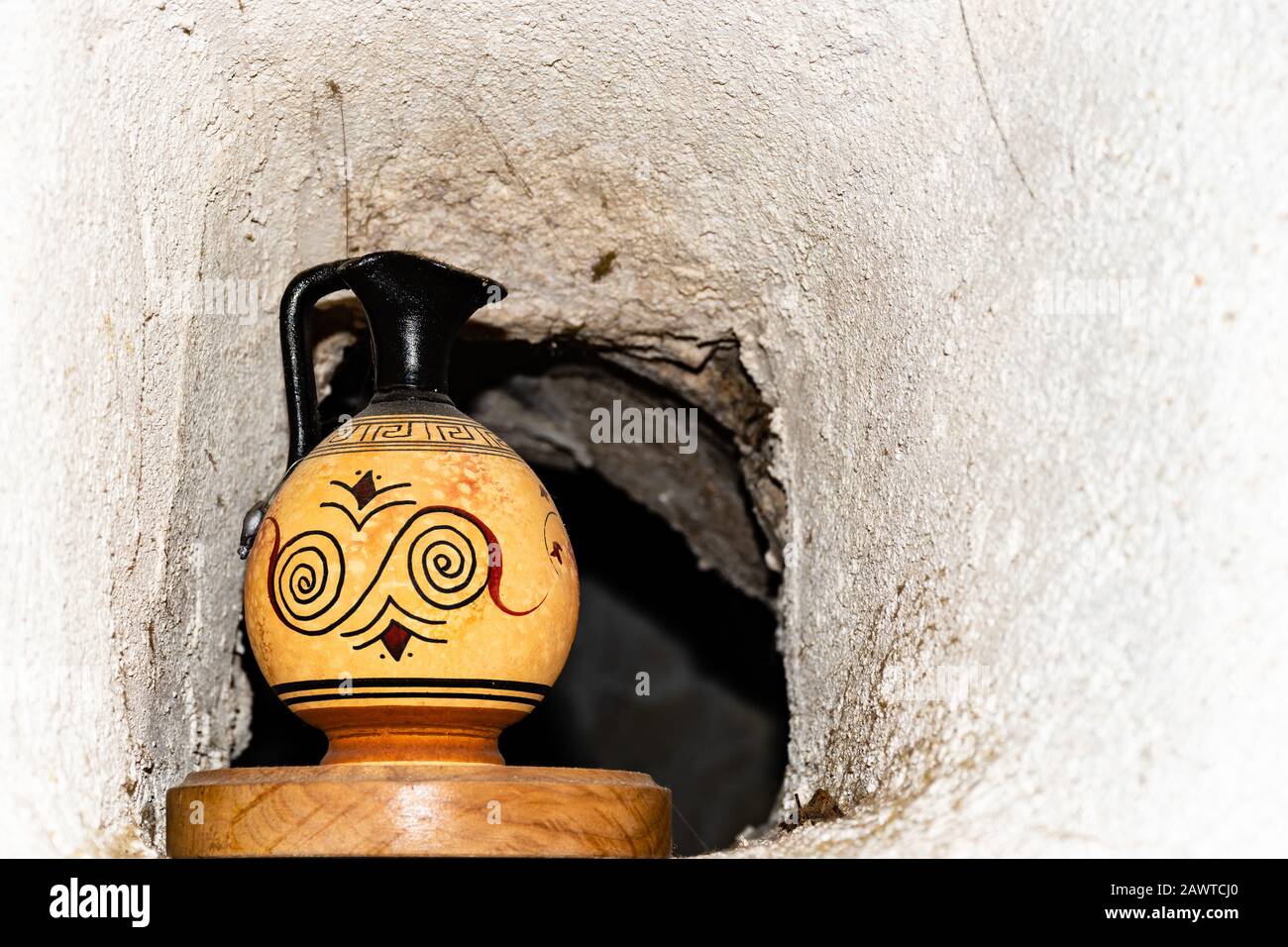Une vieille carafe en céramique sur un support en bois dans une petite fenêtre dans le mur de pierre entre les chambres dans un ancien bâtiment français Banque D'Images