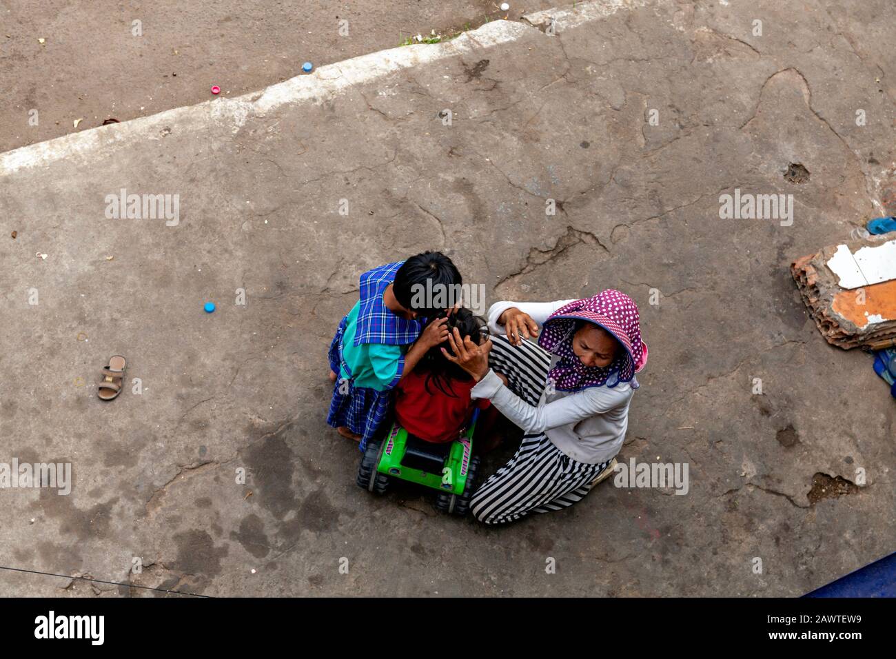 Une pauvre fille cambodgienne sans abri et une femme appauvrie qui travaillent comme des piégeurs cueillent des puces hors des cheveux d'une jeune fille à Kampong Cham, au Cambodge. Banque D'Images