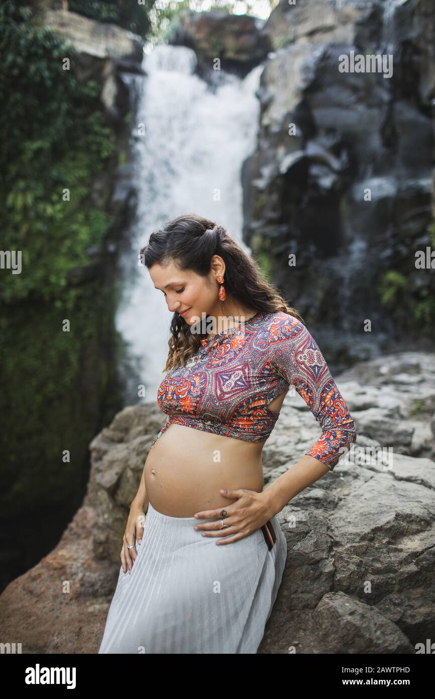 Les jeunes professionnels d'femme enceinte et de la maternité en nature plein air. Sex partners Holding belly. Harmonie avec la nature, de l'accouchement à Bali le voyage. Le bonheur de la maternité spirituelle. Banque D'Images