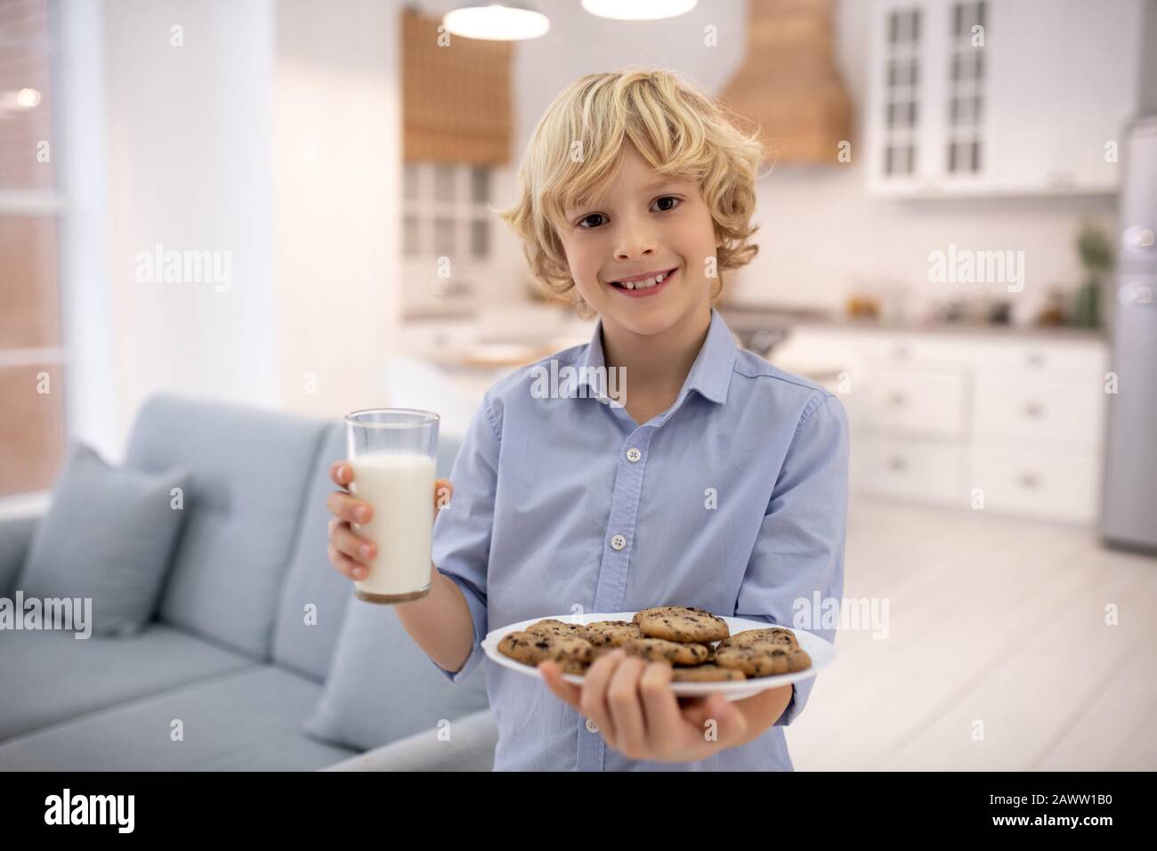 Garçon tenant un verre de lait et de biscuits Banque D'Images