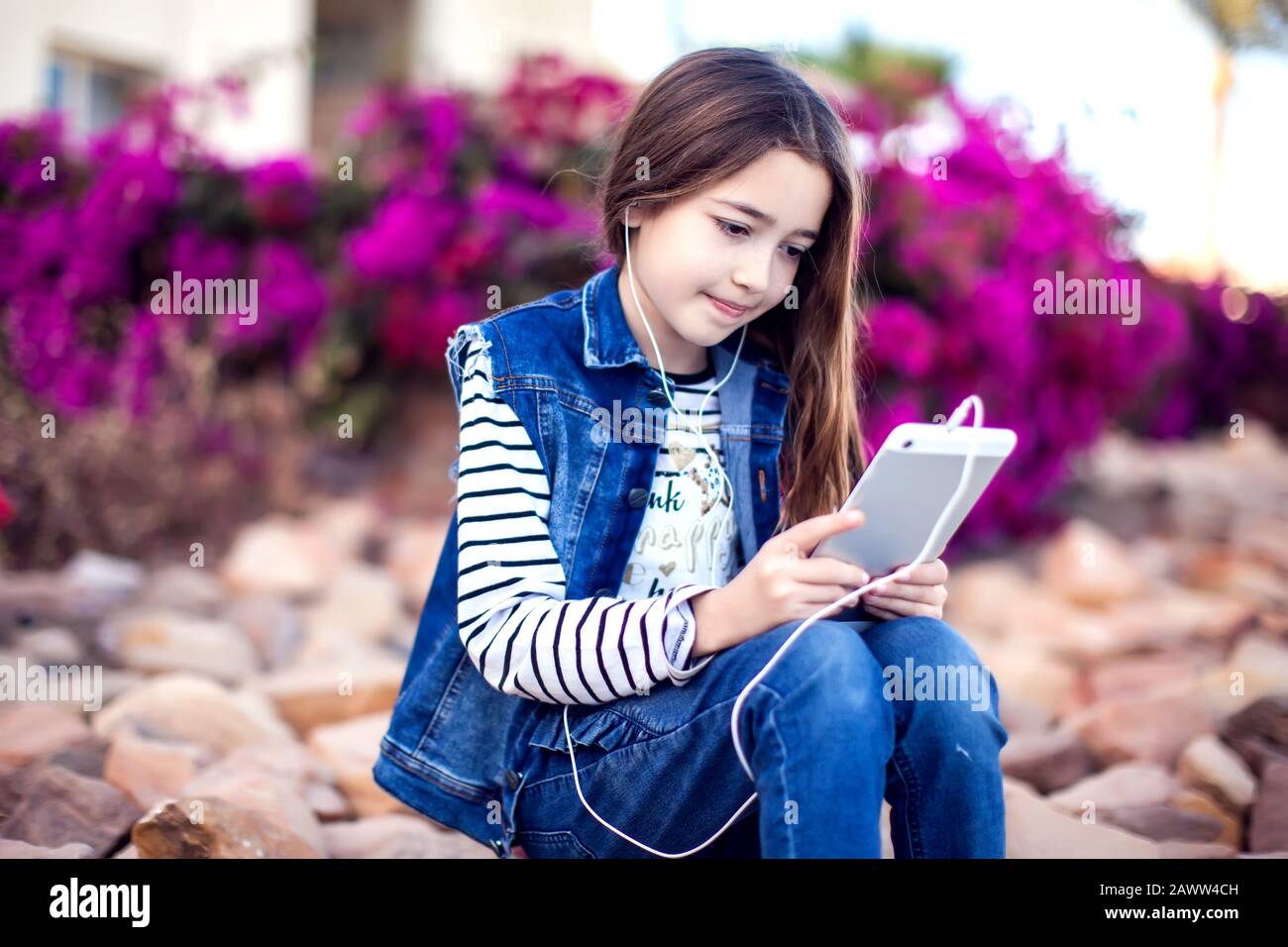 Gamin girl jouant à des jeux sur tablette en plein air. Concept de dépendance des enfants et des gadgets Banque D'Images