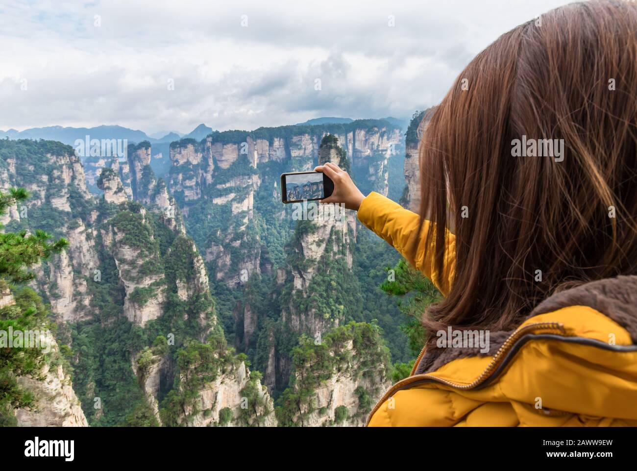 Une jeune fille touristique asiatique prend une photo à l'aide d'un smartphone au parc forestier national de Zhangjiajie, site classé au patrimoine mondial de l'UNESCO, Wulingyuan, Hunan, Chine Banque D'Images