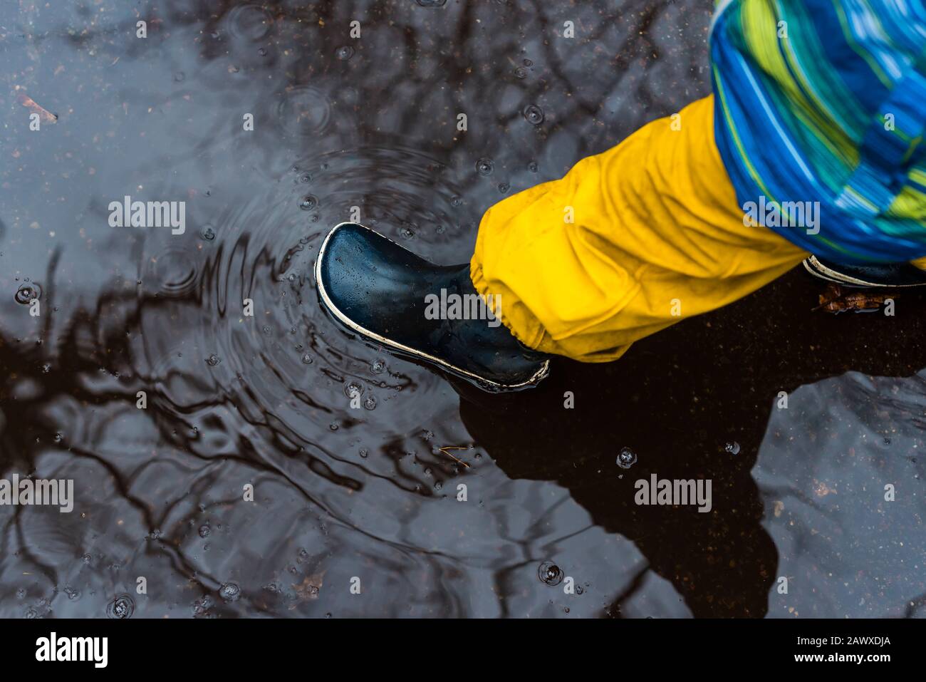 Pied pour enfant avec bottes en caoutchouc dans une flaque, jour pluvieux, hiver, automne, bottes en caoutchouc, eau Banque D'Images