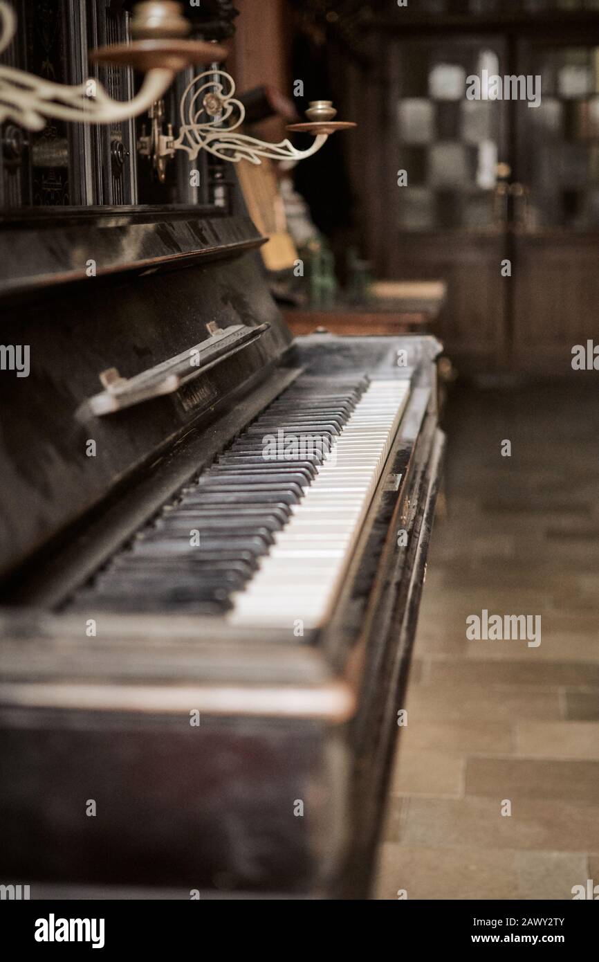 Piano brun d'époque recouvert de poussière dans une pièce ancienne. Intérieur rétro et en bois avec un look ancien. Banque D'Images
