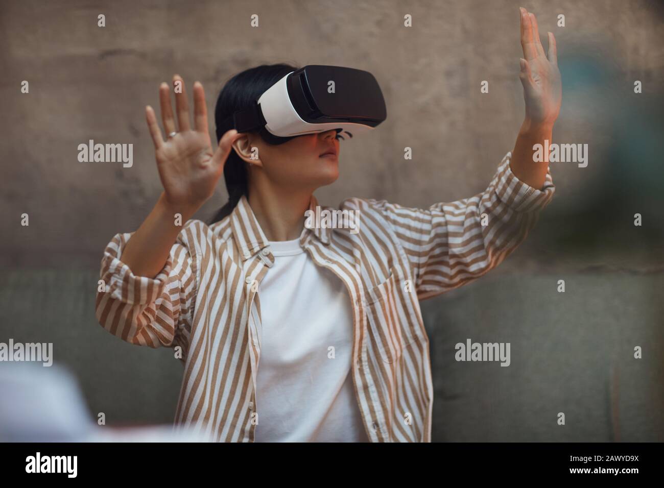 Taille haute portrait d'une femme asiatique portant un équipement VR et gestuelle tout en profitant d'une expérience immersive dans un intérieur futuriste Banque D'Images