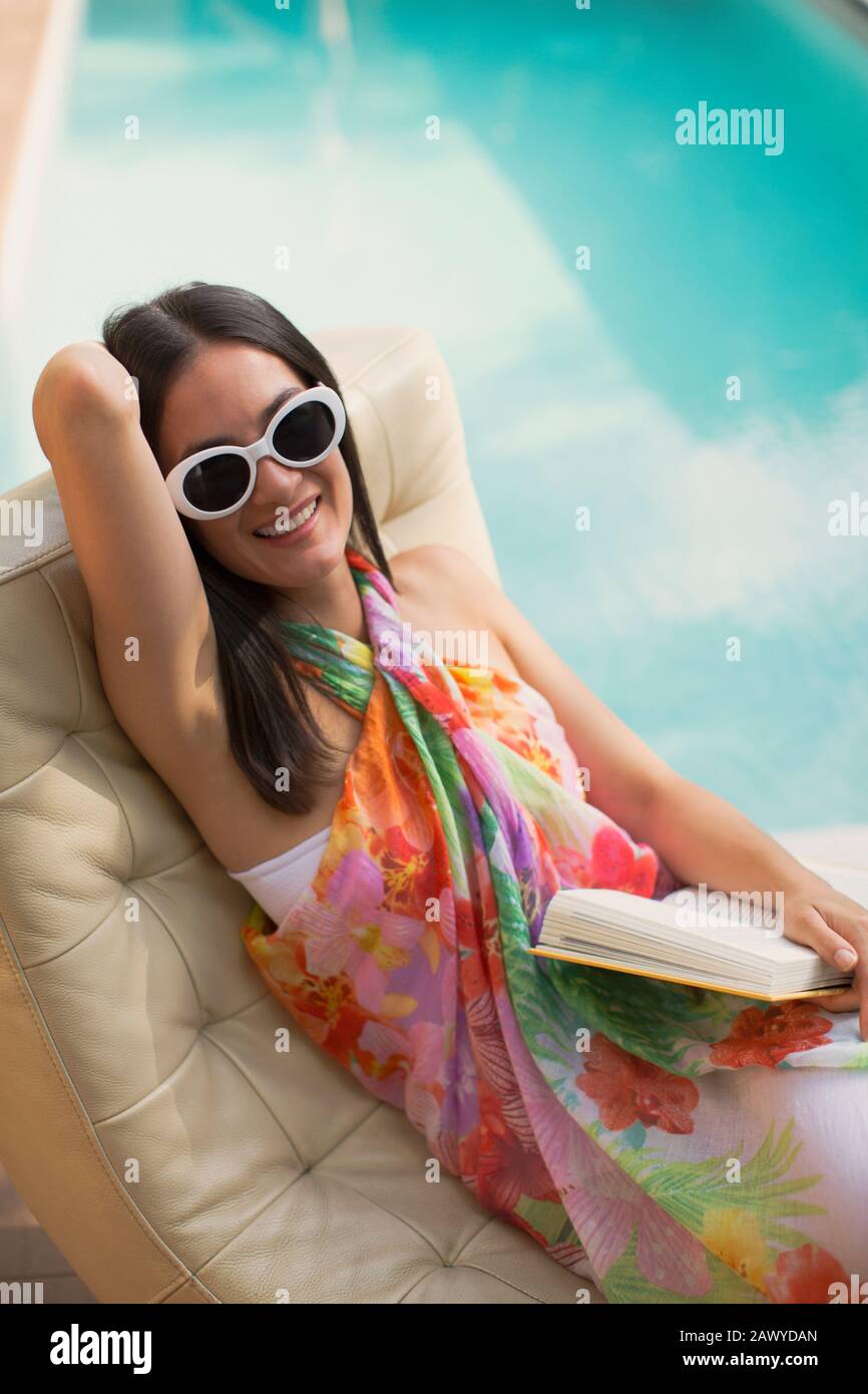 Portrait Happy woman détente, livre de lecture sur chaise longue au bord de la piscine d'été Banque D'Images