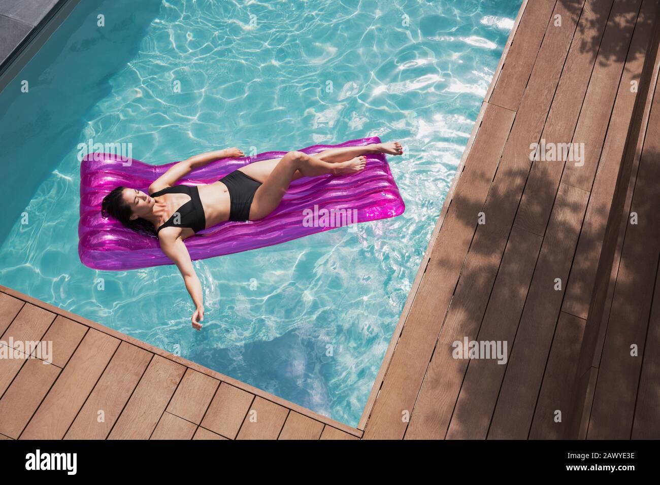Femme sereine se reposant sur un radeau gonflable dans la piscine d'été ensoleillée Banque D'Images