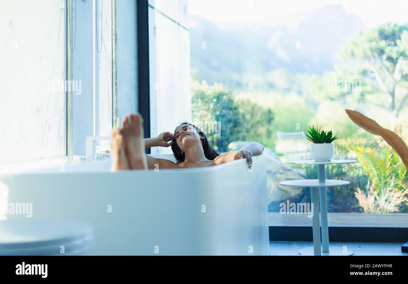 Une femme sereine se détendant dans la baignoire dans la salle de bains moderne Banque D'Images
