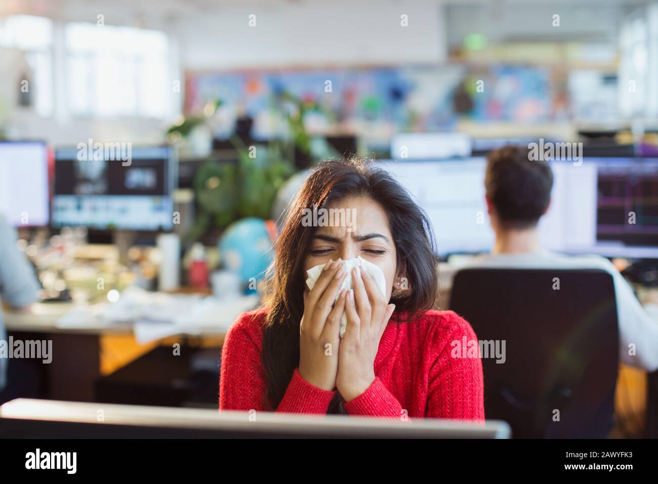 Femme d'affaires souffrant d'allergies éternuant dans les tissus à l'ordinateur au bureau Banque D'Images