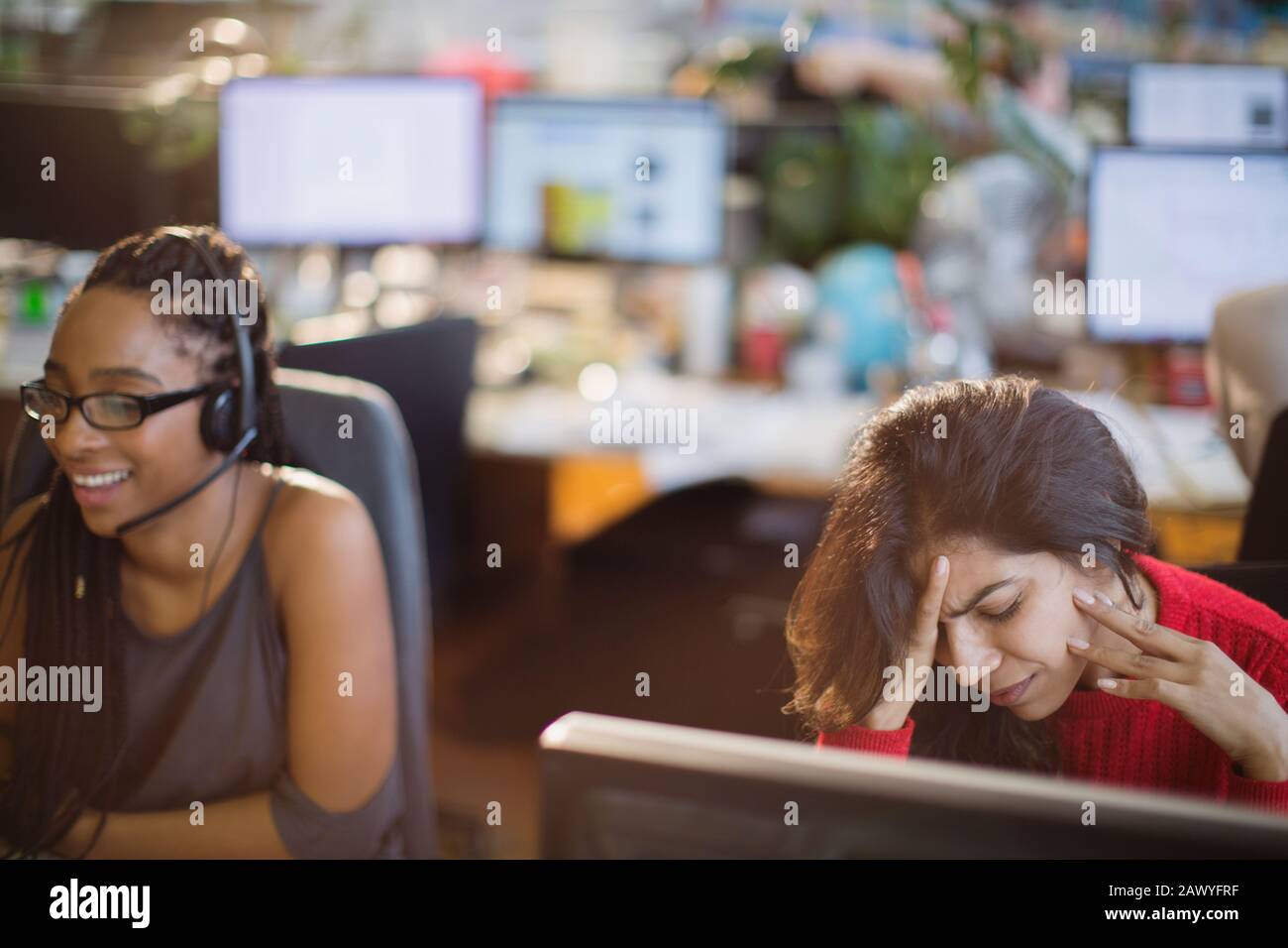 Femme d'affaires soulignée avec la tête dans les mains à l'ordinateur au bureau Banque D'Images
