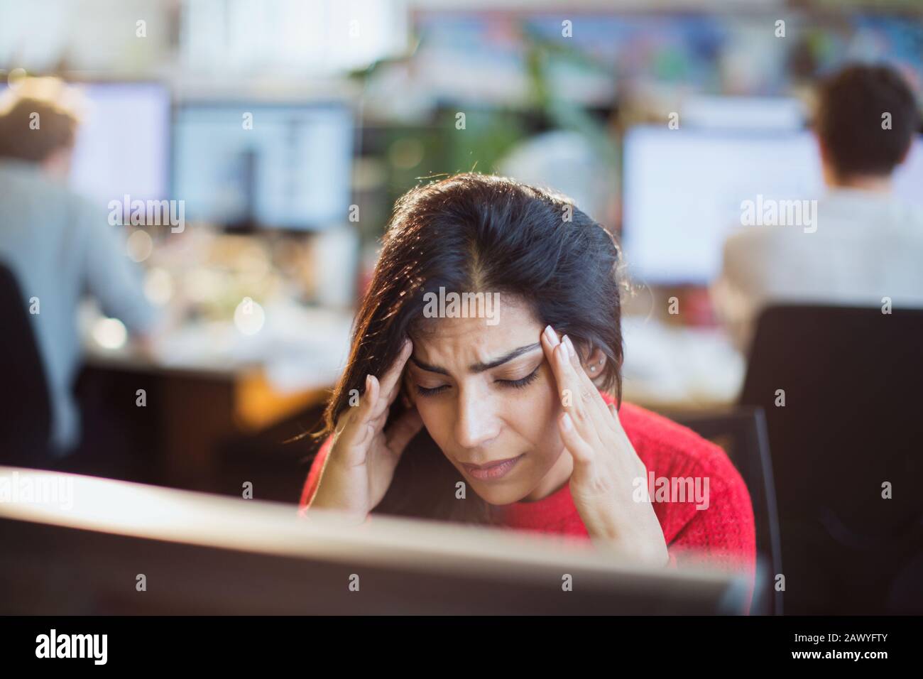 Femme d'affaires soulignée avec la tête dans les mains à l'ordinateur au bureau Banque D'Images