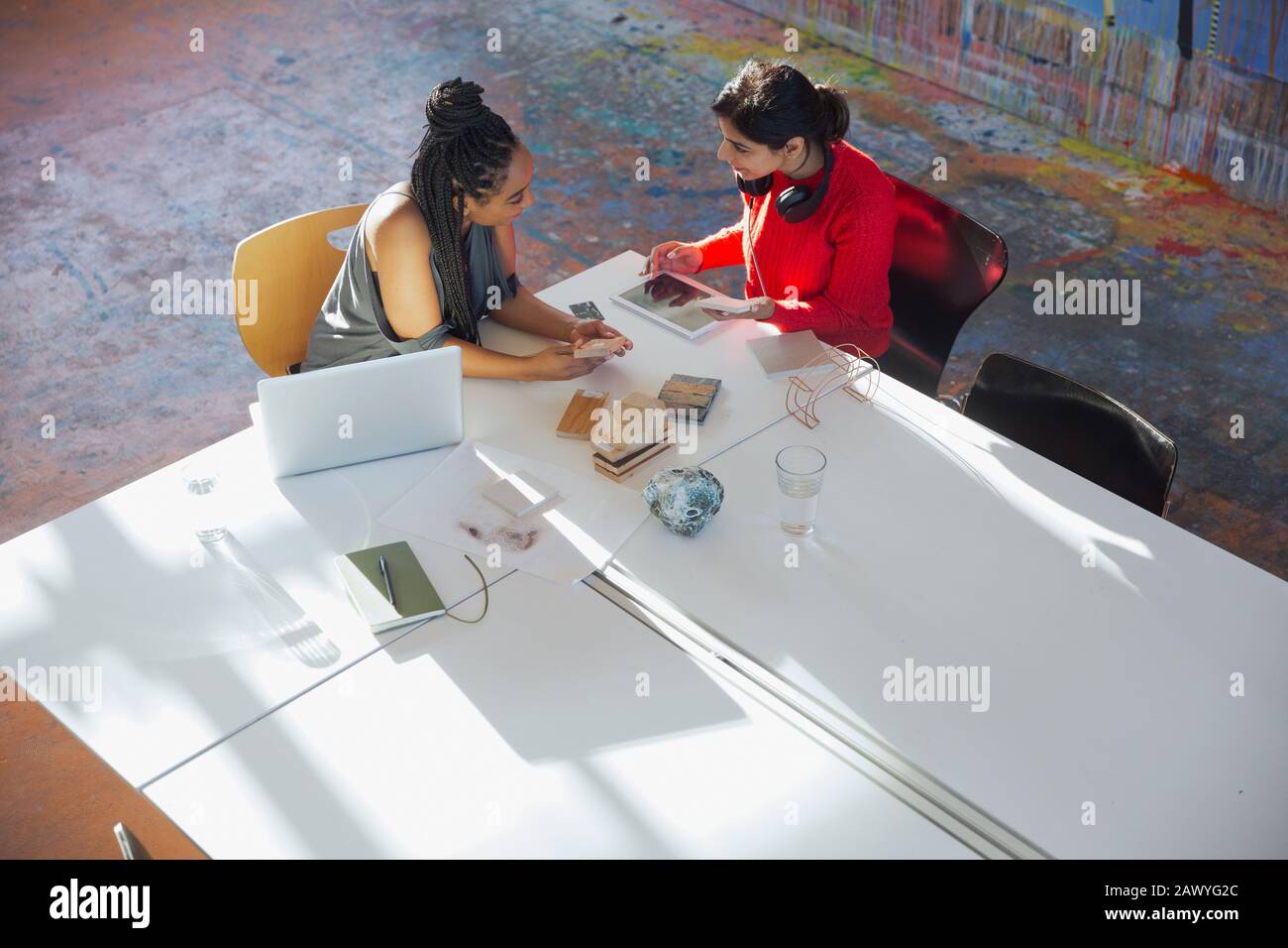 Les femmes d'affaires créatives parlent, utilisent une tablette numérique, planifient la réunion dans la salle de conférence Banque D'Images