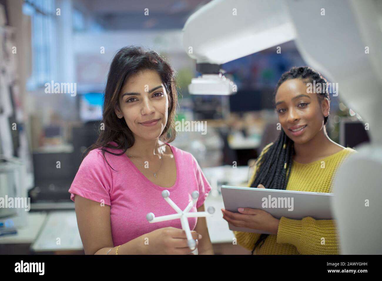 Portraits d'ingénieurs femmes confiants avec prototype et bras robotisé au bureau Banque D'Images