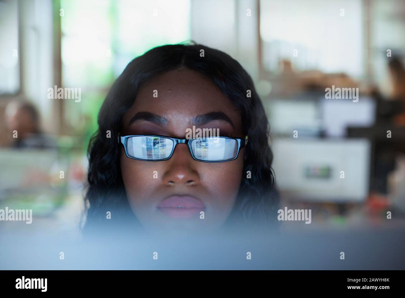 Jeune femme d'affaires ciblée dans les lunettes de vue travaillant à l'ordinateur Banque D'Images