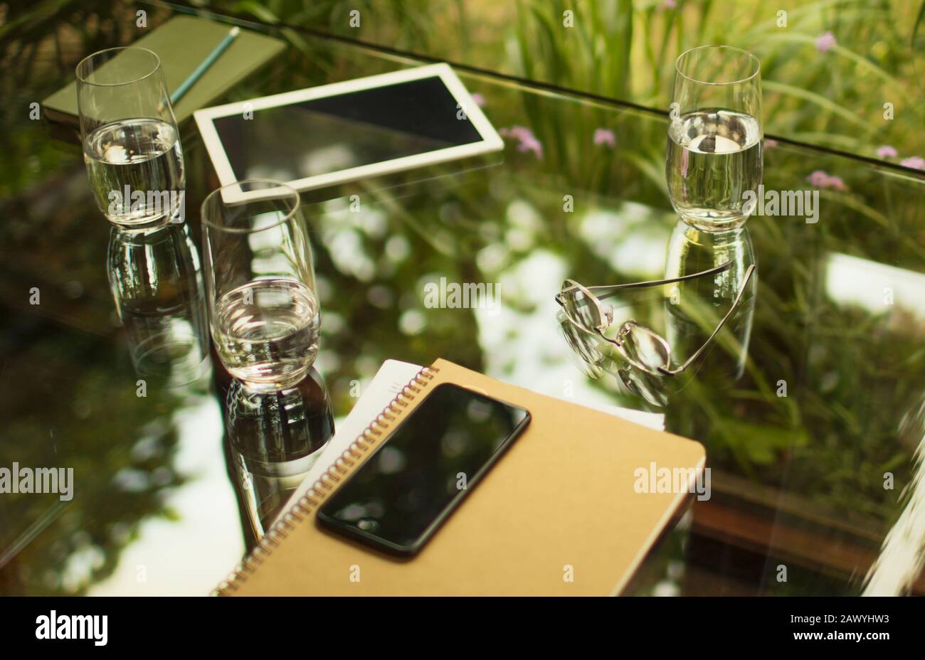 Téléphone intelligent et ordinateur portable sur table avec verres à eau Banque D'Images