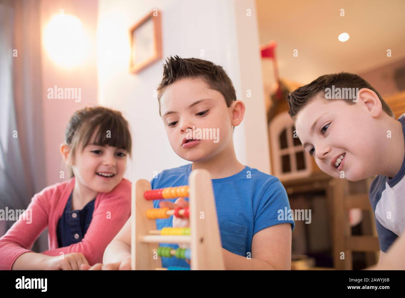 Garçon avec syndrome De Down et frères et sœurs jouant avec le jouet Banque D'Images