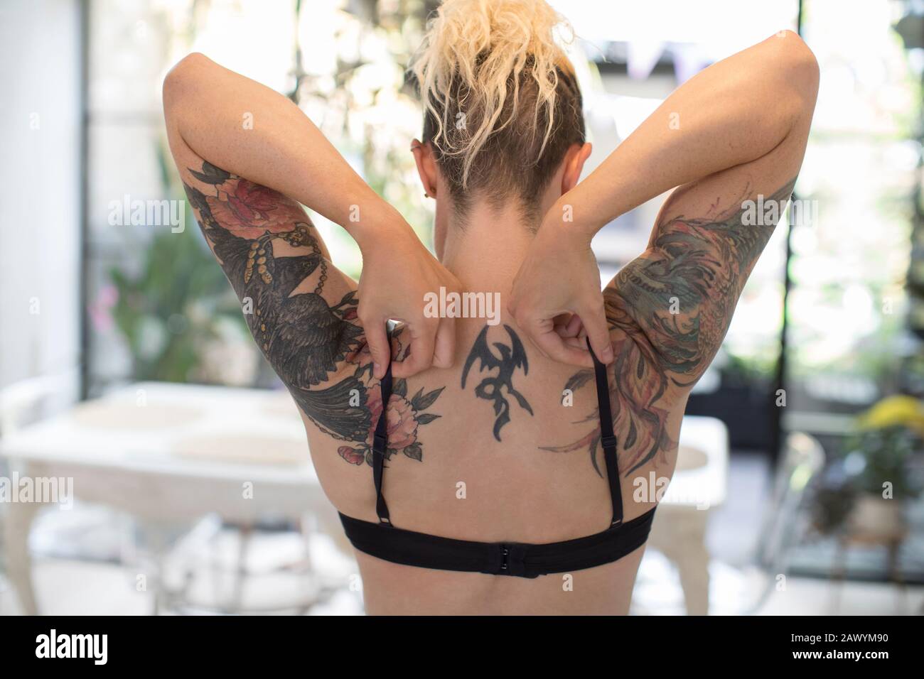 Femme avec des épaules tatouées ajustant les bretelles de soutien-gorge Banque D'Images