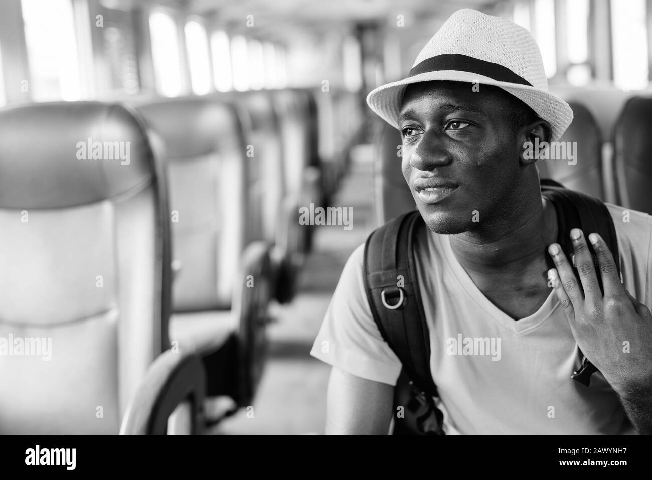Jeune homme de tourisme africain heureux regardant à l'extérieur de la fenêtre pendant que vous conduisez le train Banque D'Images