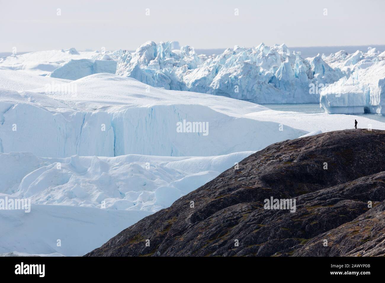 Homme sur la falaise surplombant les majestueux glaciers polaires Groenland Banque D'Images