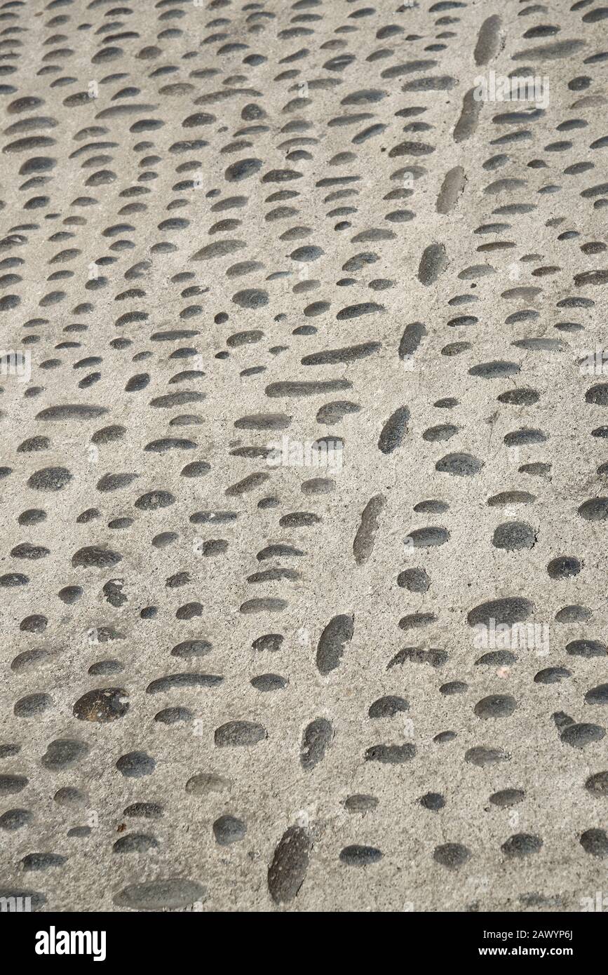 Une rue avec de petites pierres noires en ciment. Surface de route pavée. Banque D'Images