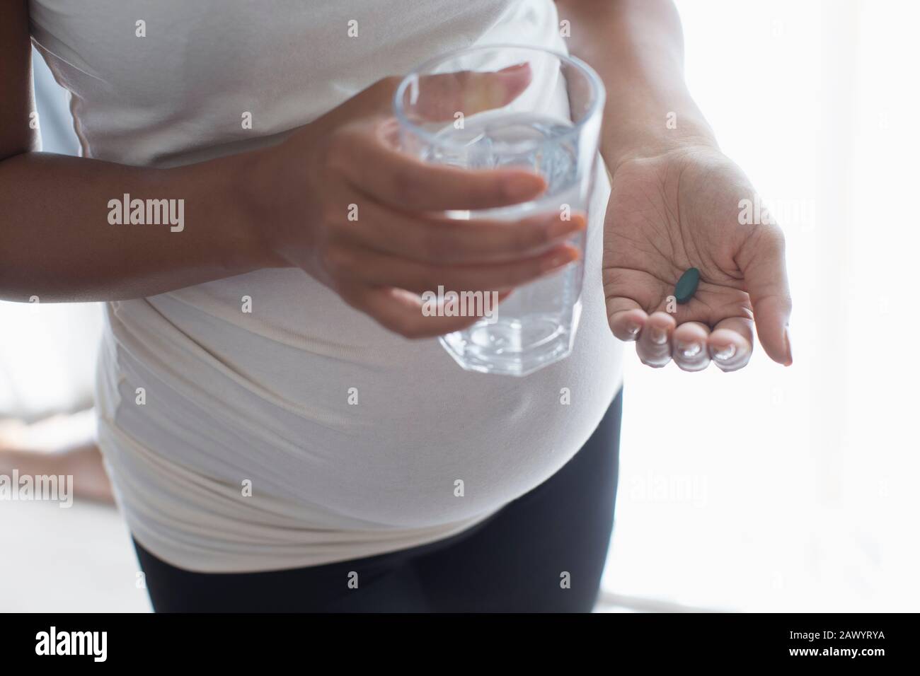 Gros plan femme enceinte prenant de la vitamine avec de l'eau Banque D'Images
