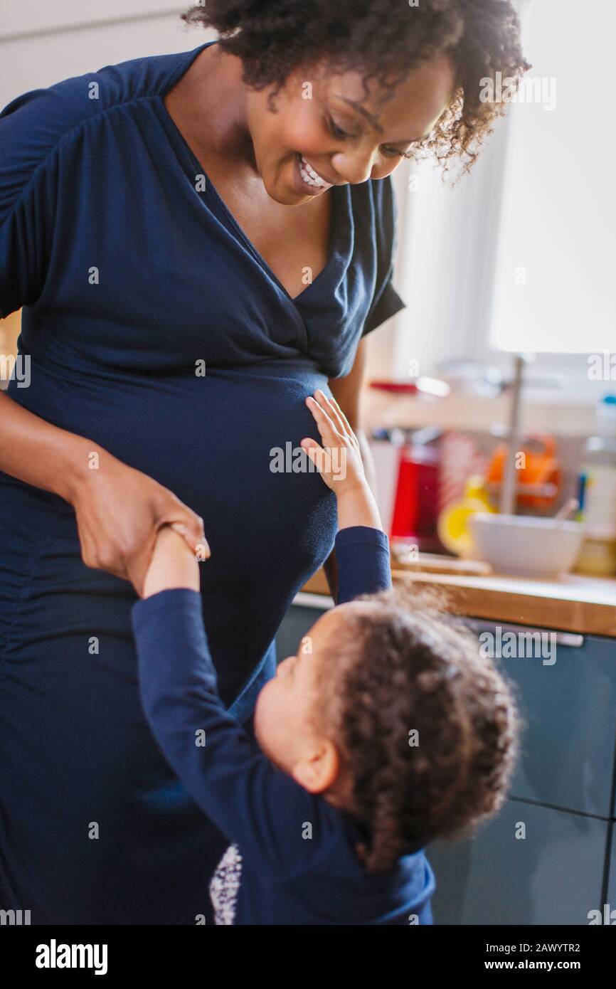 Fille curieuse touchant l'estomac de la mère enceinte Banque D'Images