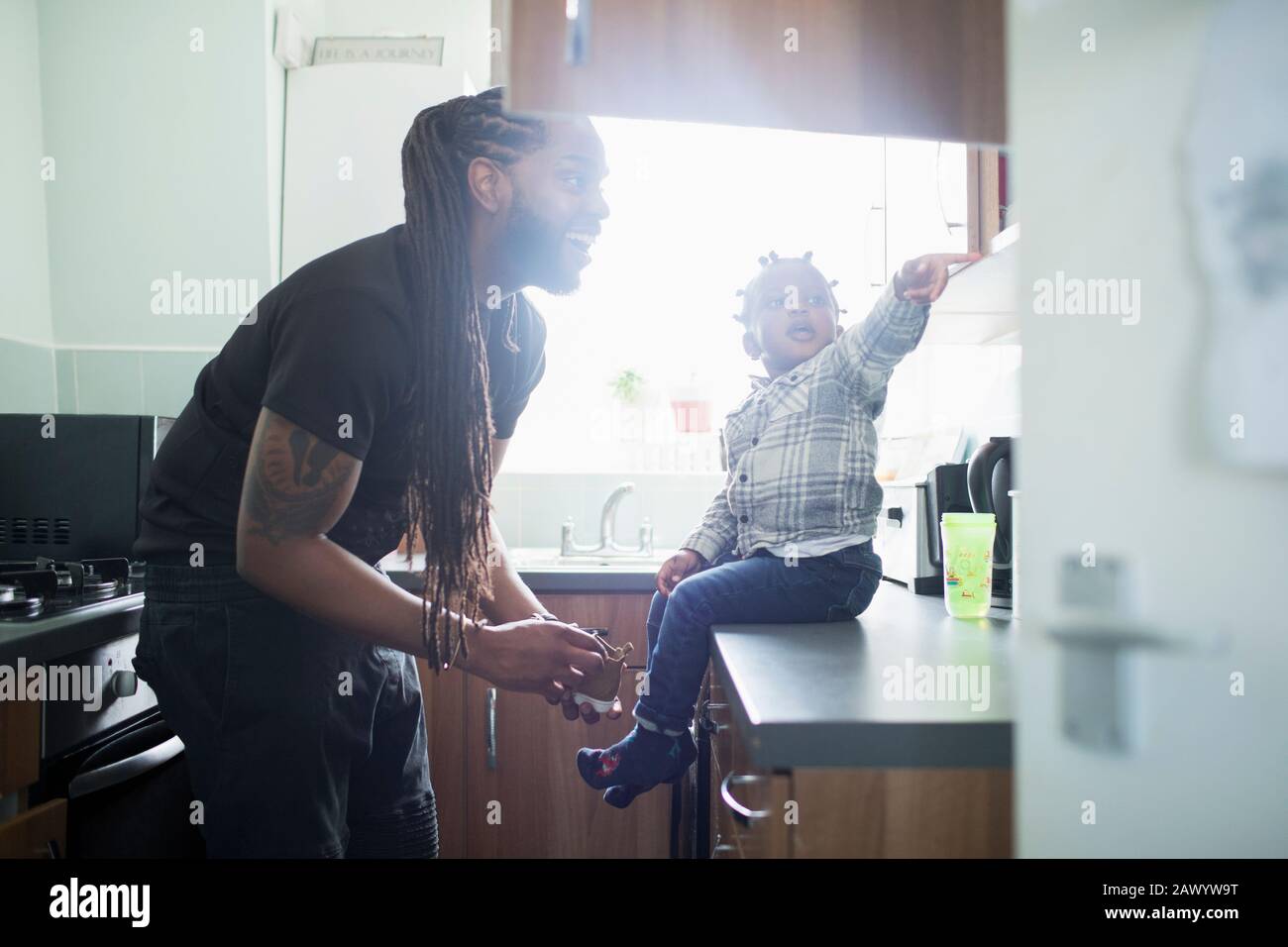 Heureux père fils mettant des chaussures sur le petit enfant dans la cuisine Banque D'Images