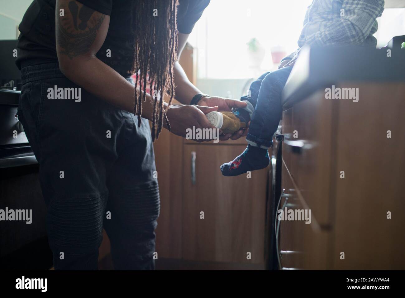 Père mettant des chaussures sur le petit enfant Banque D'Images