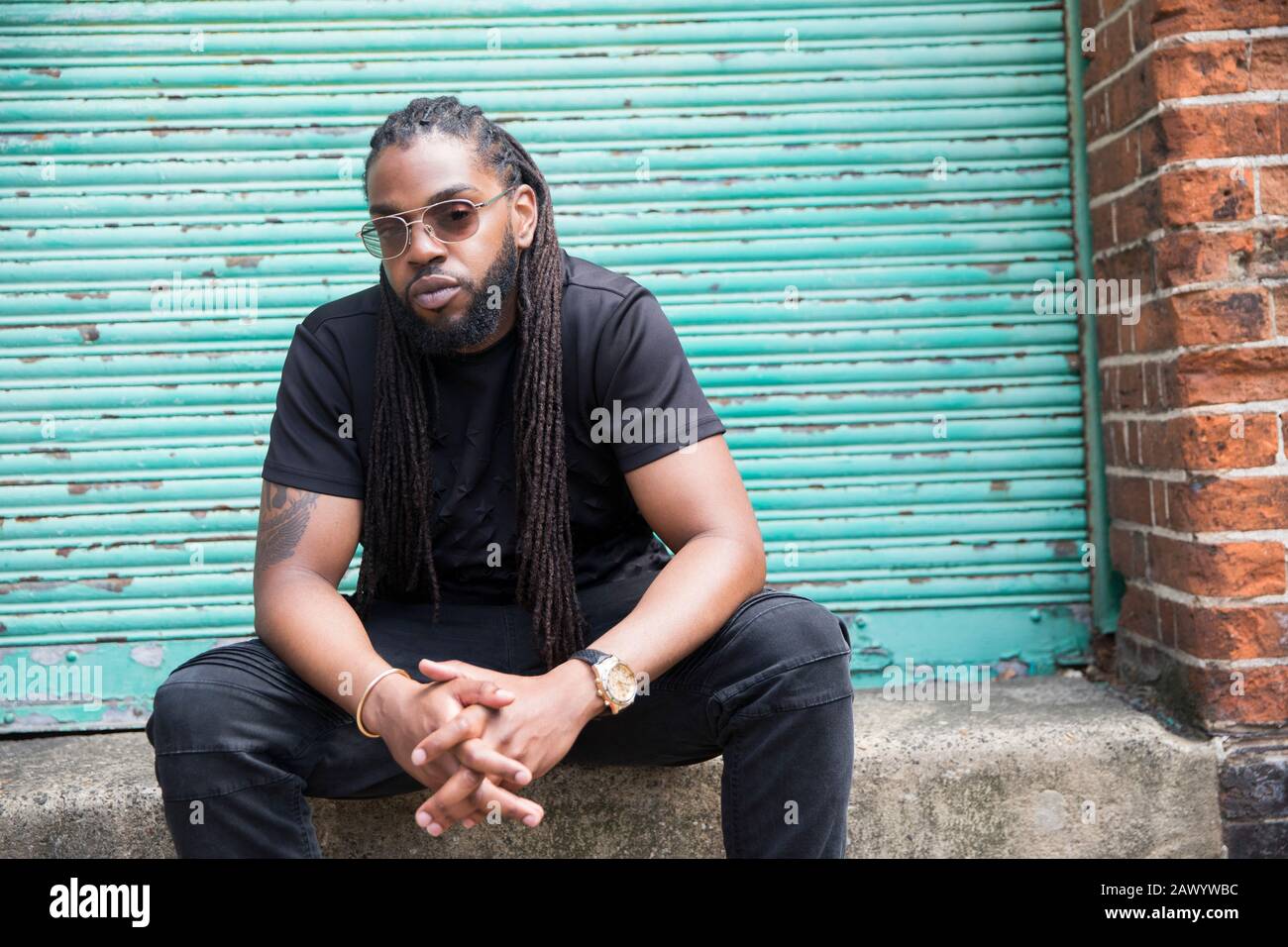 Portrait confiant homme cool avec de longues tresses dans la ruelle urbaine Banque D'Images