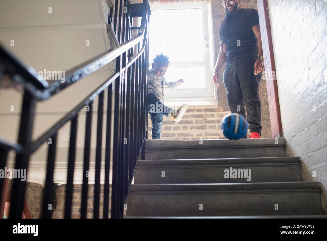 Père et jeune fils jouant avec le ballon de football sur l'atterrissage d'escalier Banque D'Images