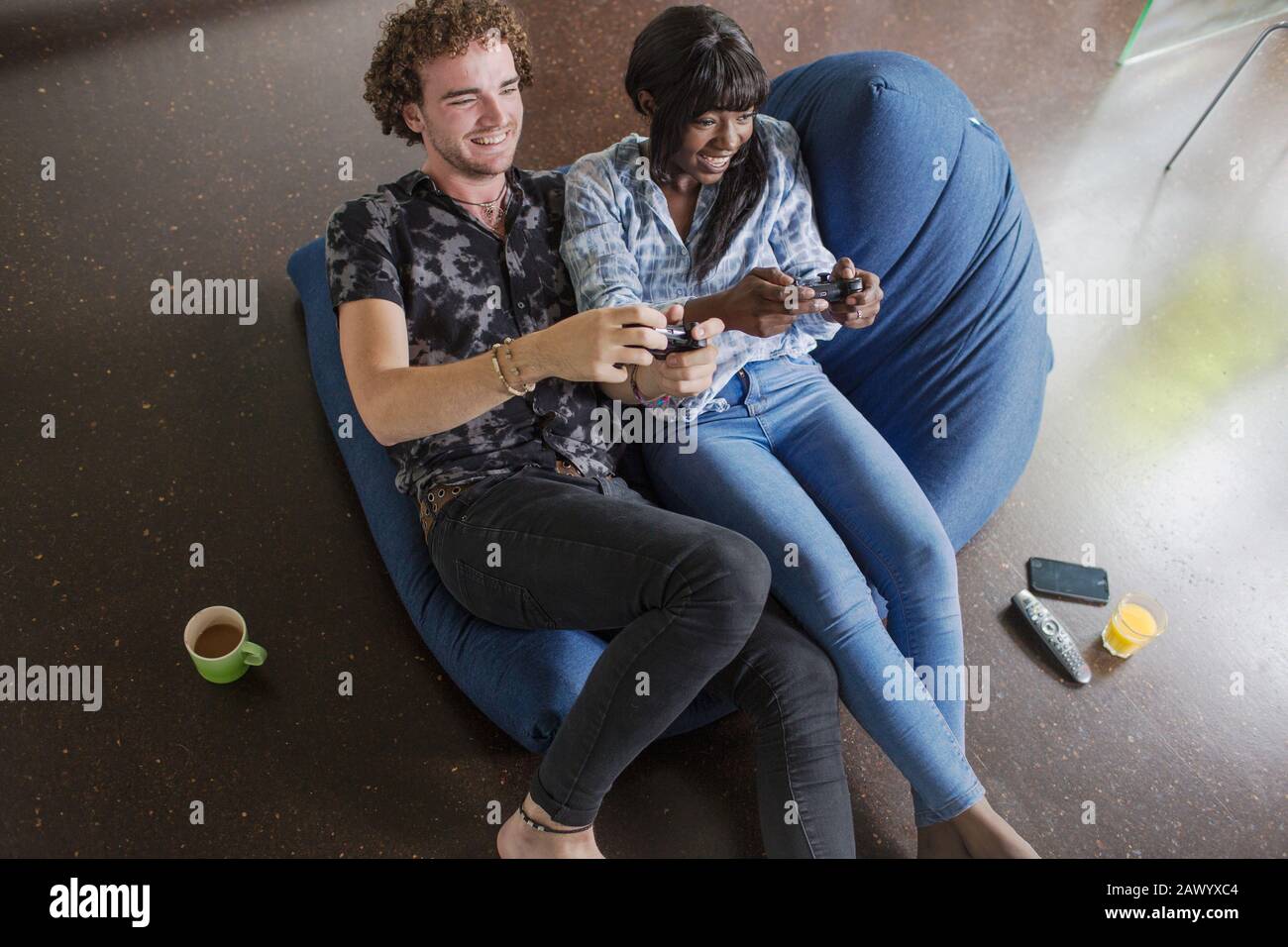 Joyeux jeune couple jouant au jeu vidéo sur chaise beanbag Banque D'Images