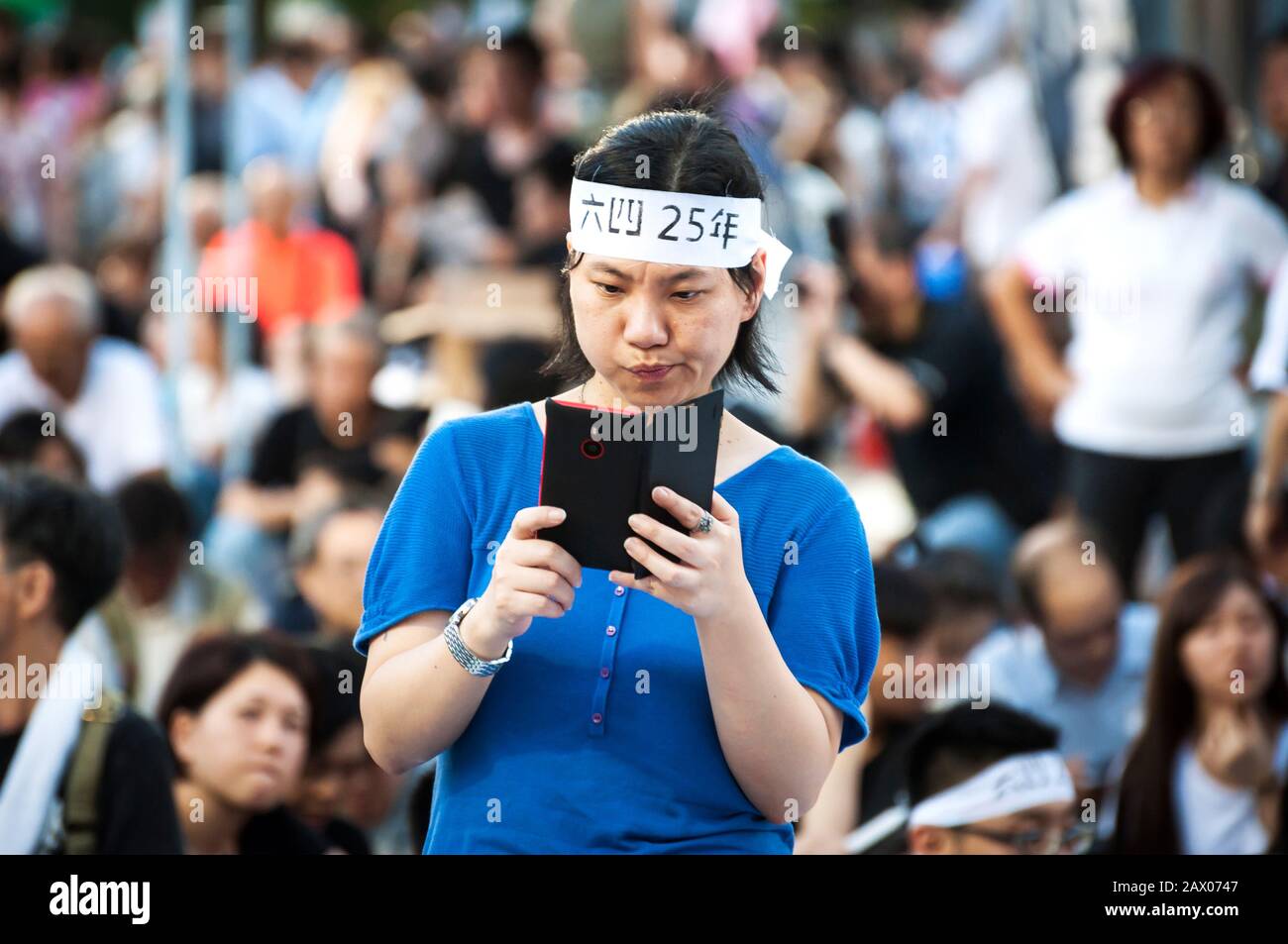 Femme portant un bandeau prend une photo lors de la commémoration du 25e anniversaire du masacre de la place Tienanmen à Victoria Park, Hong Kong Banque D'Images Femme portant un bandeau prend une photo lors de la commémoration du 25e anniversaire du masacre de la place Tienanmen à Victoria Park, Hong Kong Banque D'Images