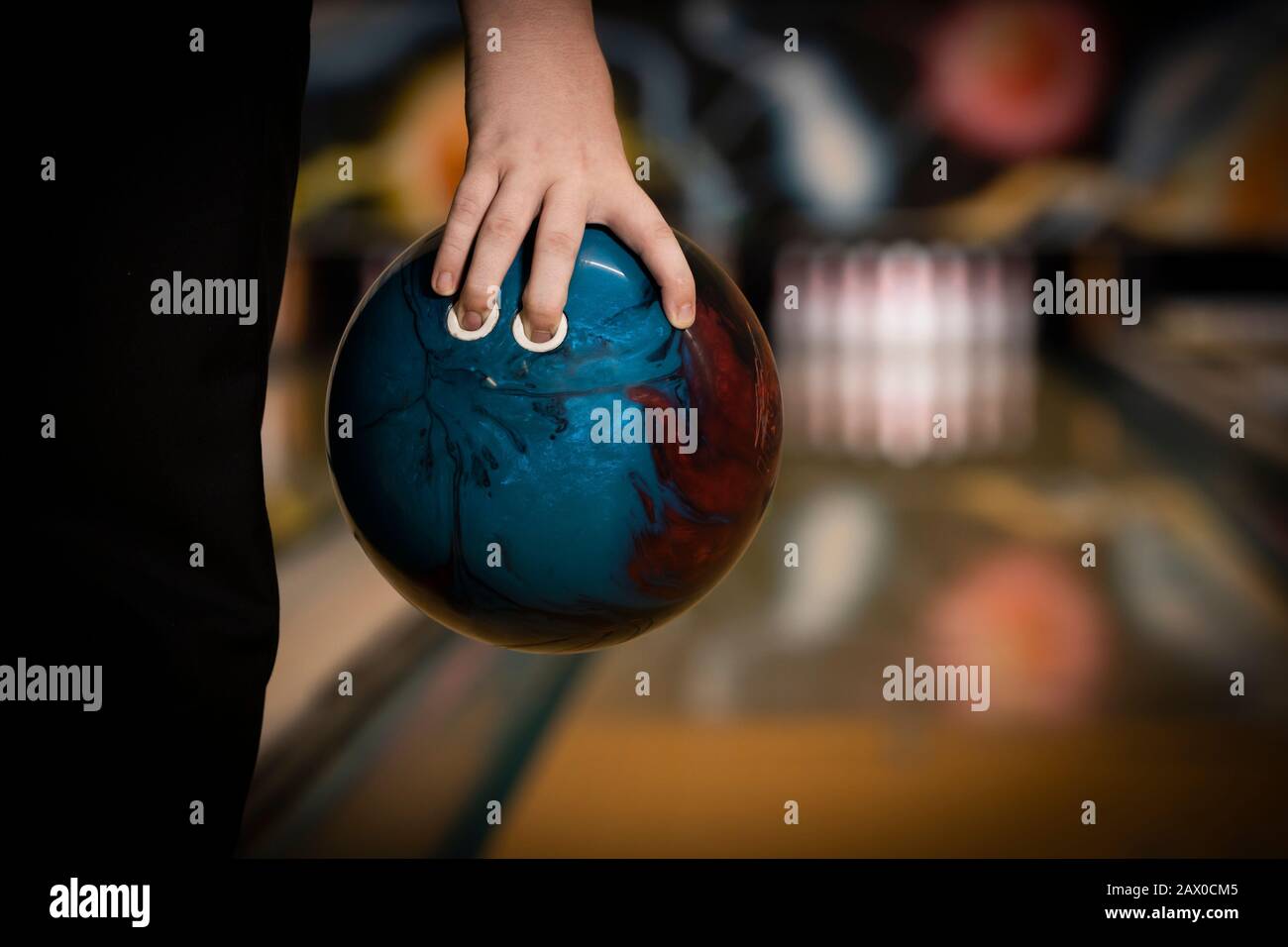 une boule de bowling à dix broches se tient à portée de main, avec piste de bowling et fond de pins Banque D'Images