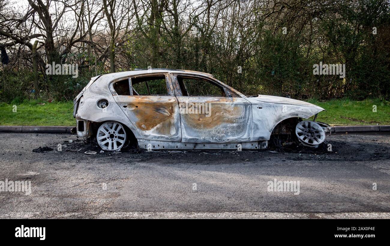 Une voiture brûlée a été abandonnée du côté de la route d'un endroit rural calme. Banque D'Images