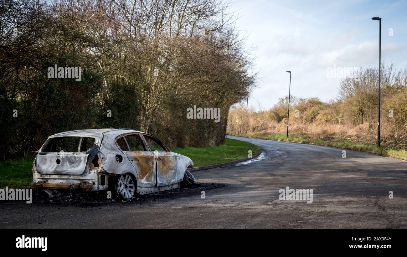 Une voiture brûlée a été abandonnée du côté de la route d'un endroit rural calme. Banque D'Images