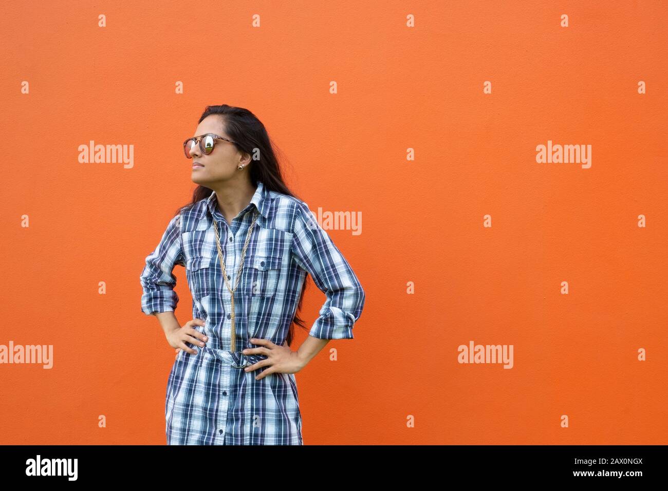 Portrait d'une jeune femme latine debout devant un mur orange , Panama, Amérique centrale Banque D'Images