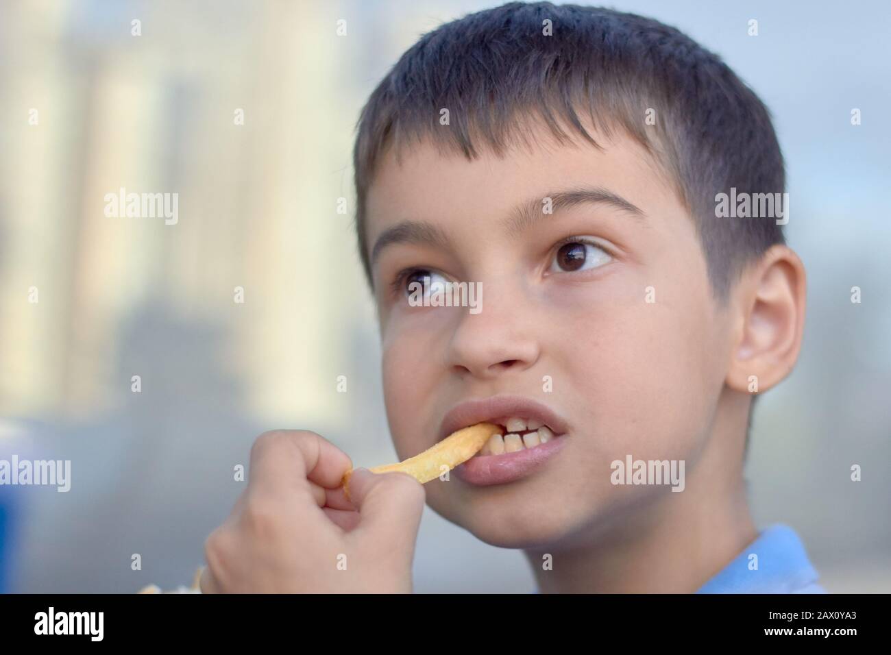 Portrait d'un petit garçon mangeant des frites. Banque D'Images