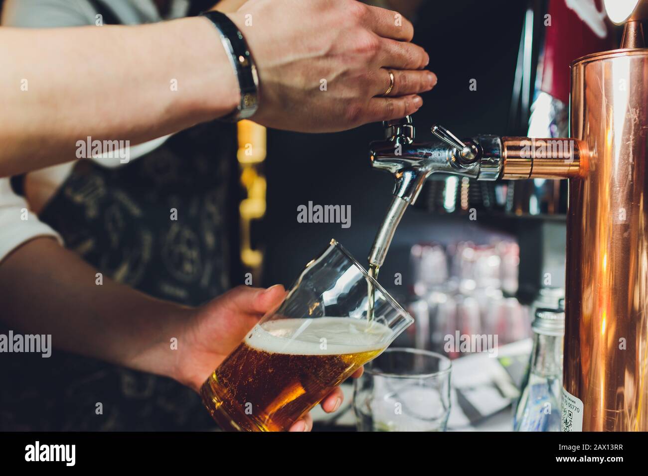 Close up d'un mâle de la bière à la distribution de barman dans un pub et tenant un grand verre tankard sous un robinet pièce jointe sur un fût en acier inoxydable Banque D'Images