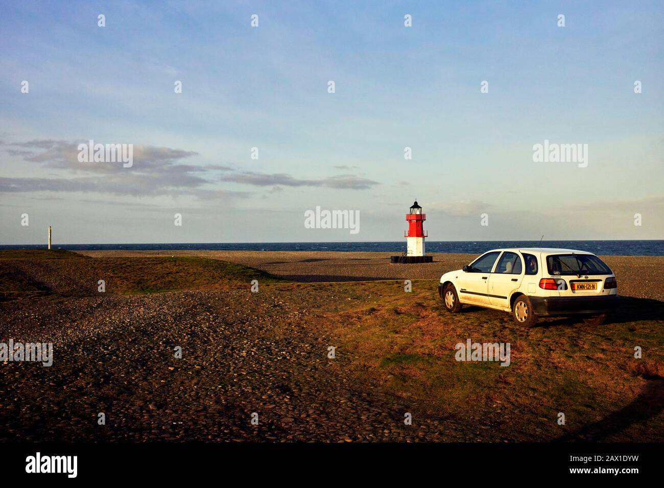 Une voiture stationnée sur un terrain accidenté à côté de la plage et du phare Winkie au point d'Ayre sur l'île de Man Banque D'Images