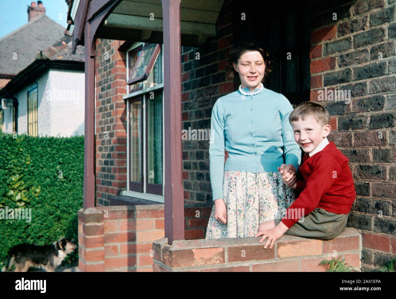 Garçon de six ans avec sa mère à l'extérieur d'un bungalow en 1960 Banque D'Images