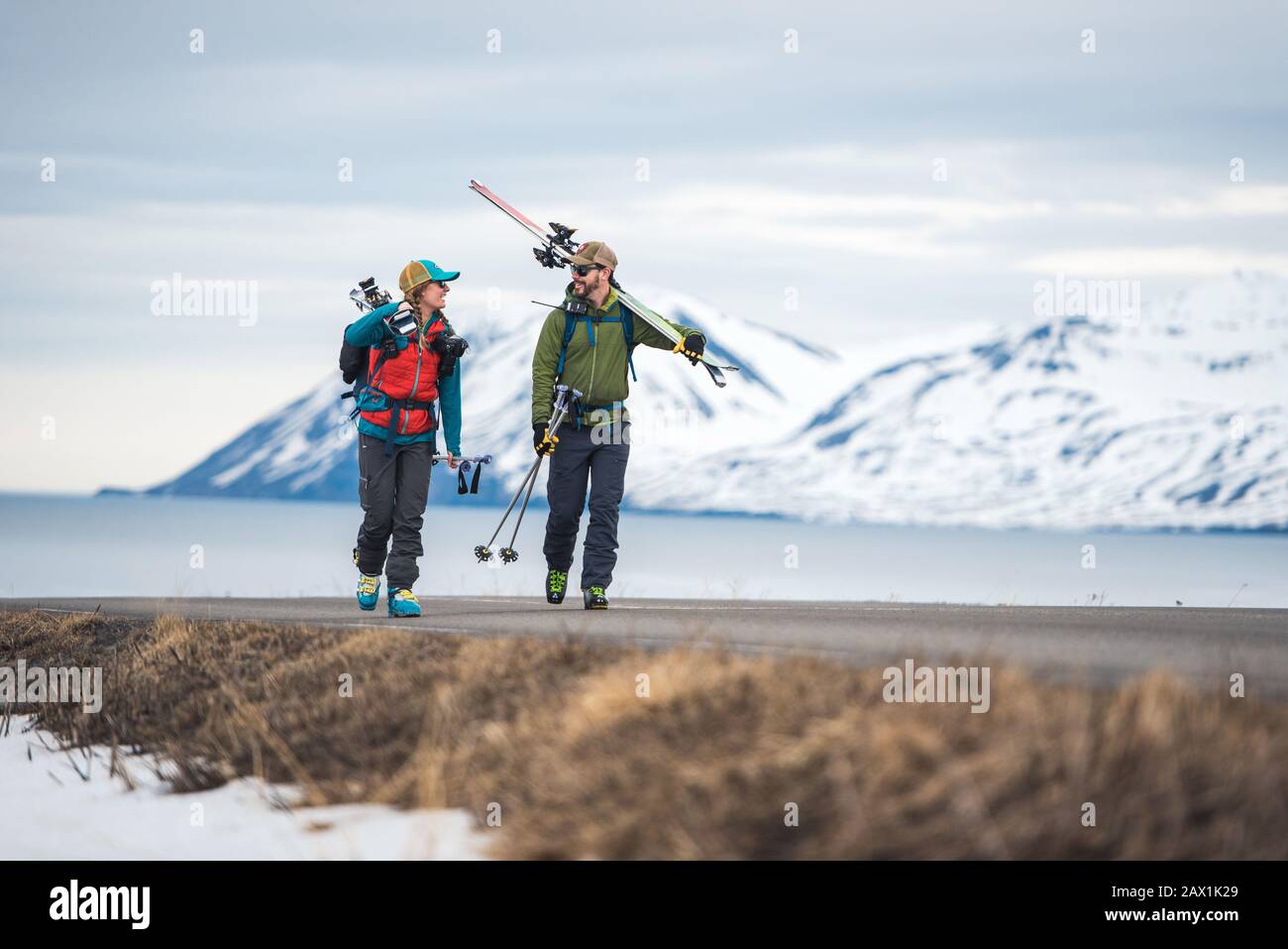 Un couple descend une route en Islande avec des skis Banque D'Images