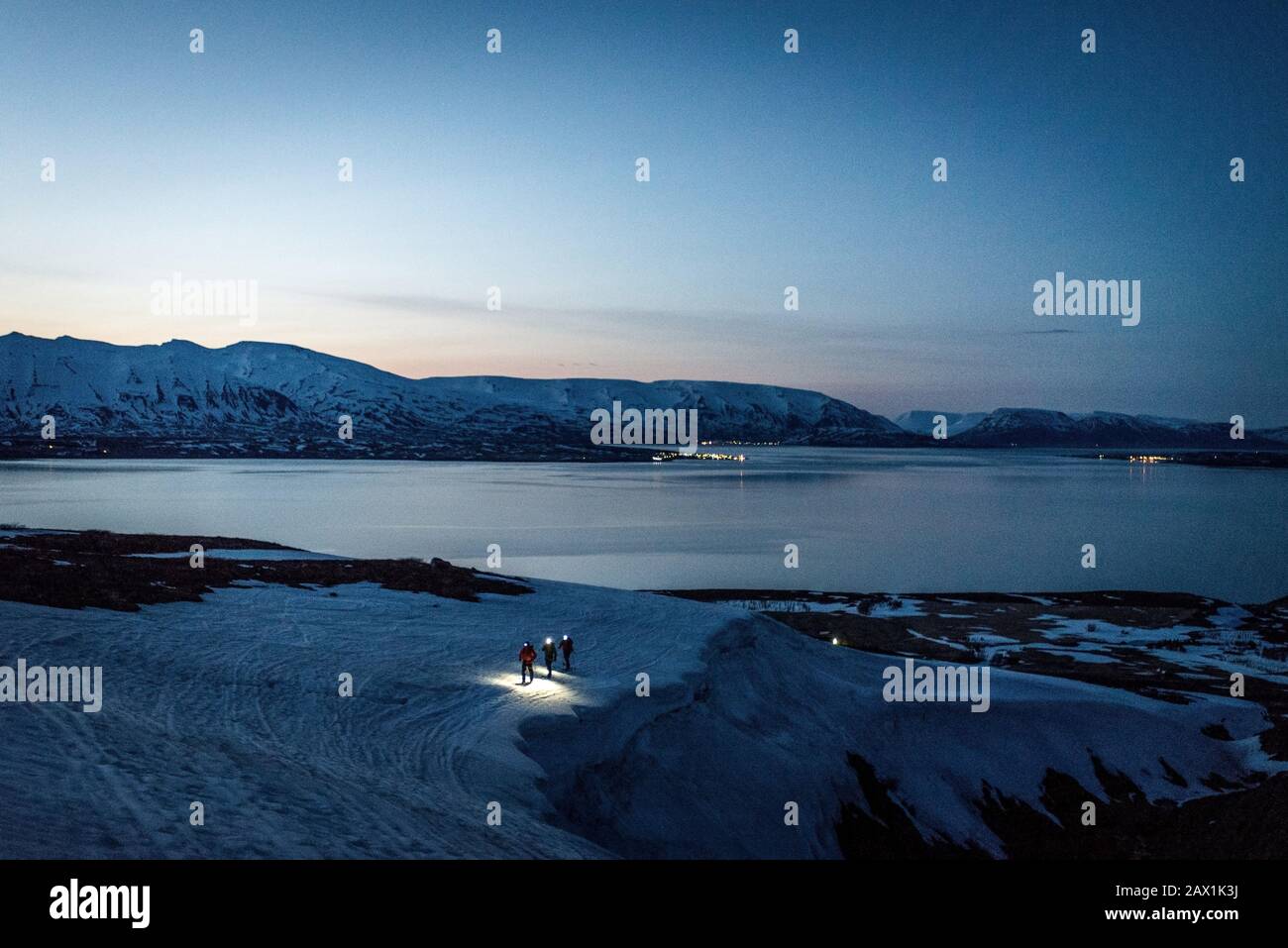 Un groupe de 3 personnes se fait des skis au lever du soleil avec l'océan et les montagnes derrière Banque D'Images
