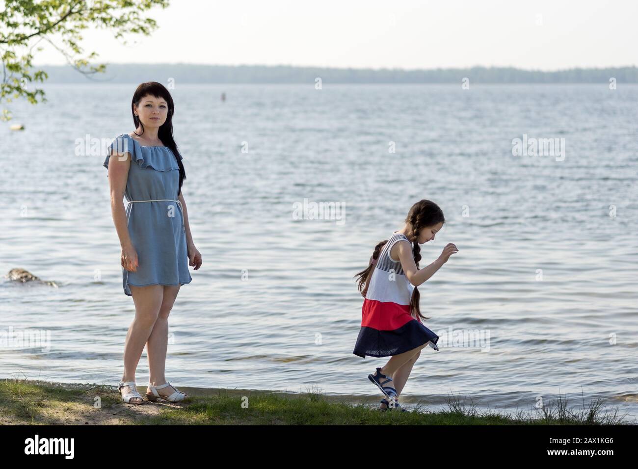 Maman avec une fille sur le lac. Une petite fille joue près de l'eau. Banque D'Images