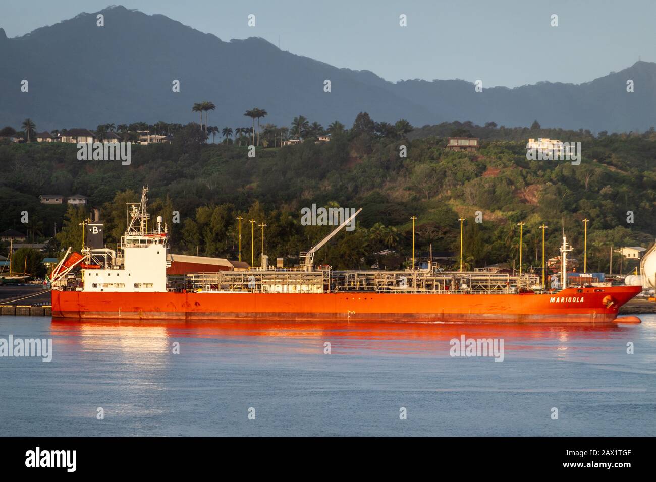 Nawiliwili, Kauai, Hawaï, États-Unis. - 16 janvier 2020: Feu de tôt le matin sur le camion-citerne GPL Marigola rouge dans le port sous ciel bleu clair. Ceinture verte en pente. B Banque D'Images