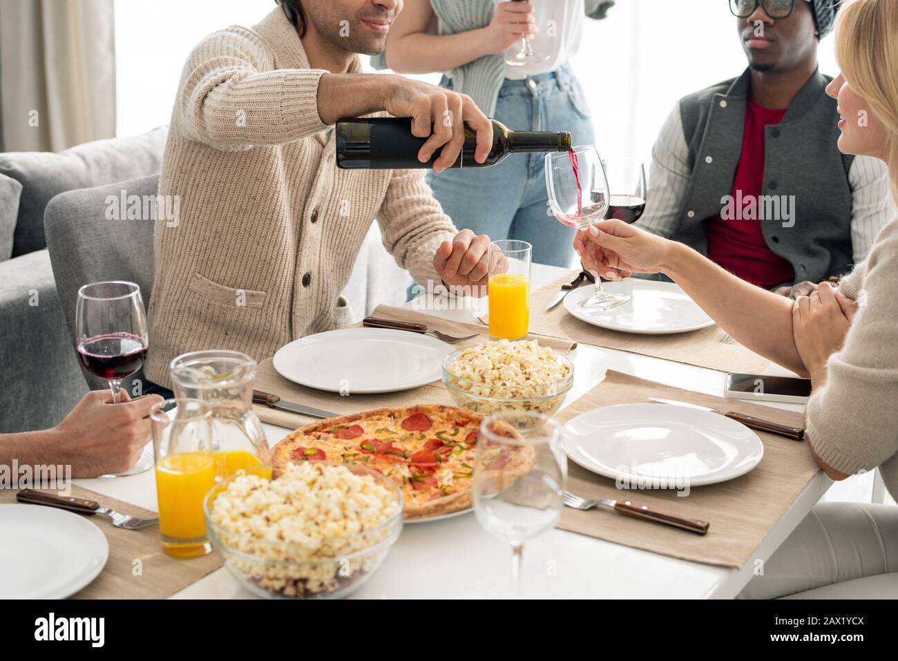Homme inconnu assis à la table du dîner avec ses amis qui couchent du vin dans des verres, prise horizontale Banque D'Images