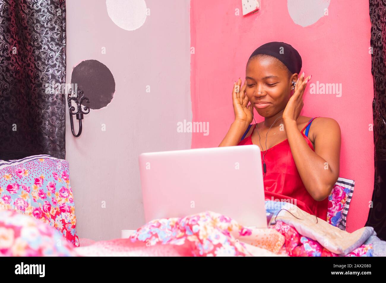 jolie dame africaine à la maison seule dans sa chambre, regarder un film sur son ordinateur portable Banque D'Images
