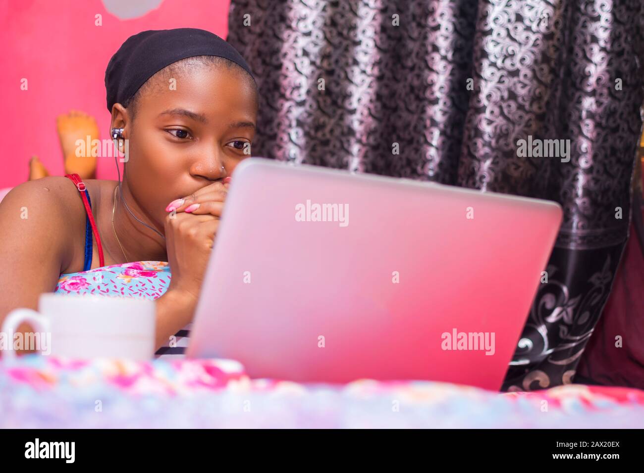 jolie dame africaine à la maison seule dans sa chambre, regarder un film sur son ordinateur portable a l'air effrayé et inconfortable Banque D'Images