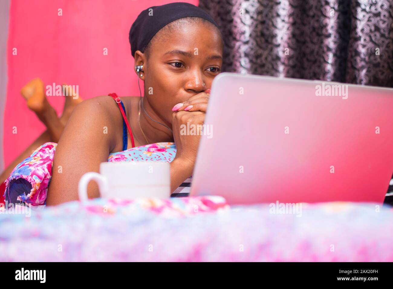 jolie dame africaine à la maison seule dans sa chambre, regarder un film sur son ordinateur portable a l'air effrayé et inconfortable Banque D'Images