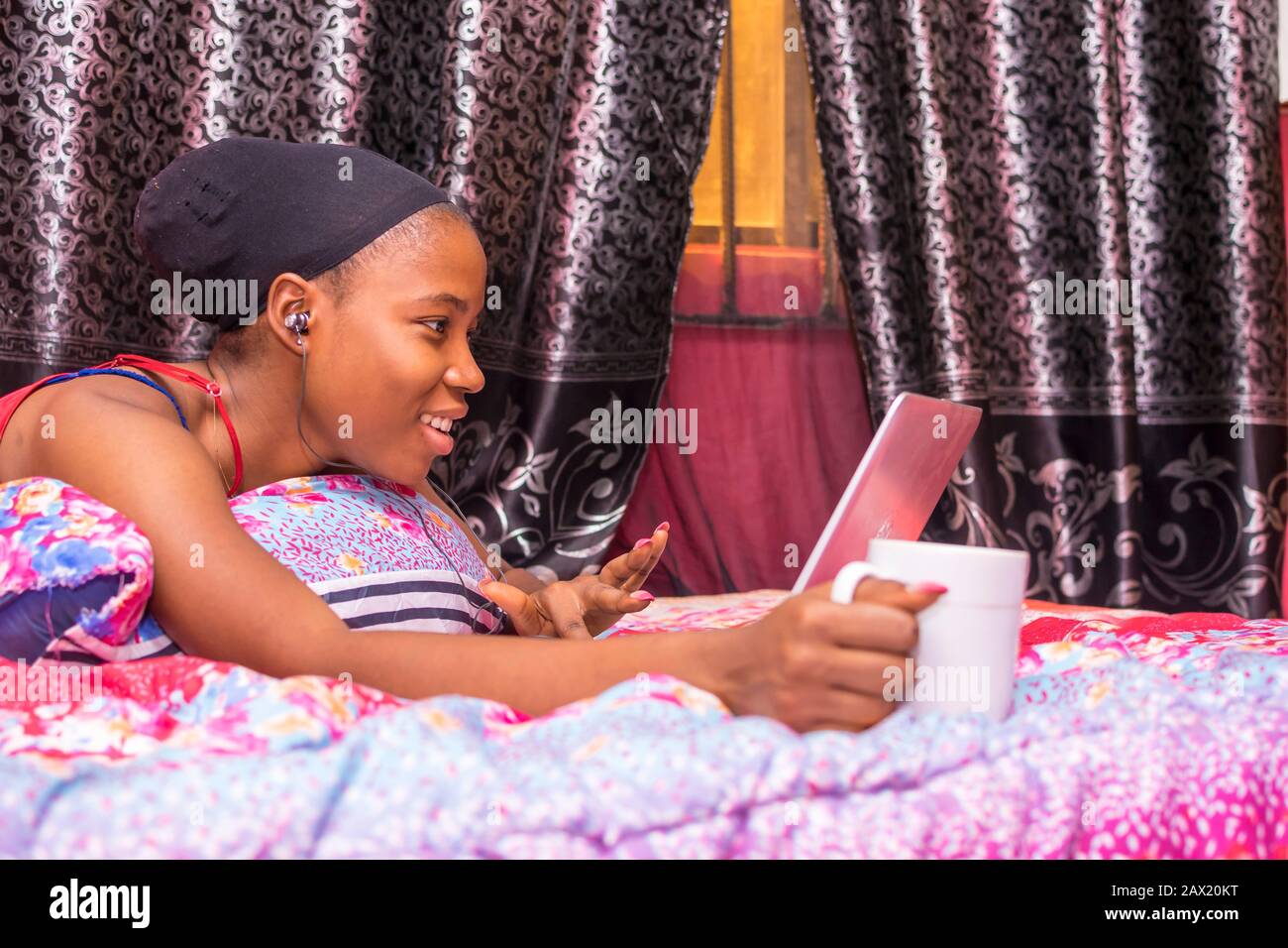 jolie dame africaine à la maison seule dans sa chambre, regarder un film sur son ordinateur portable Banque D'Images